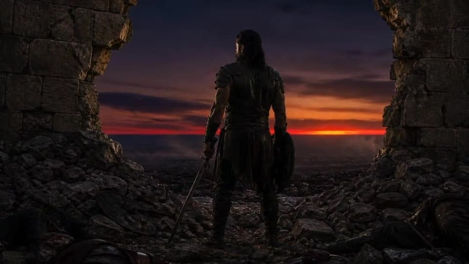A lone soldier with sword and shield standing in the gap of a broken city wall at dusk